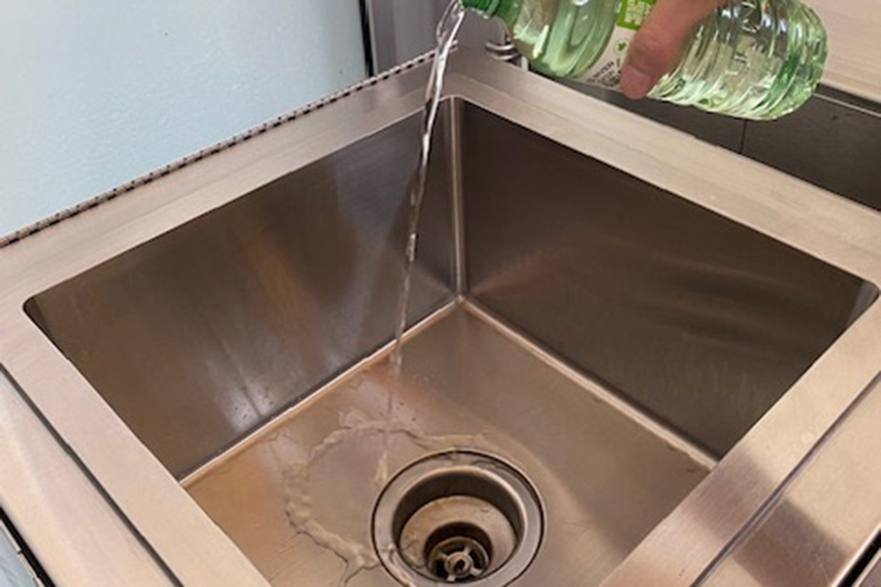 Water bottle contents being dumped into liquid disposal system (down drain)