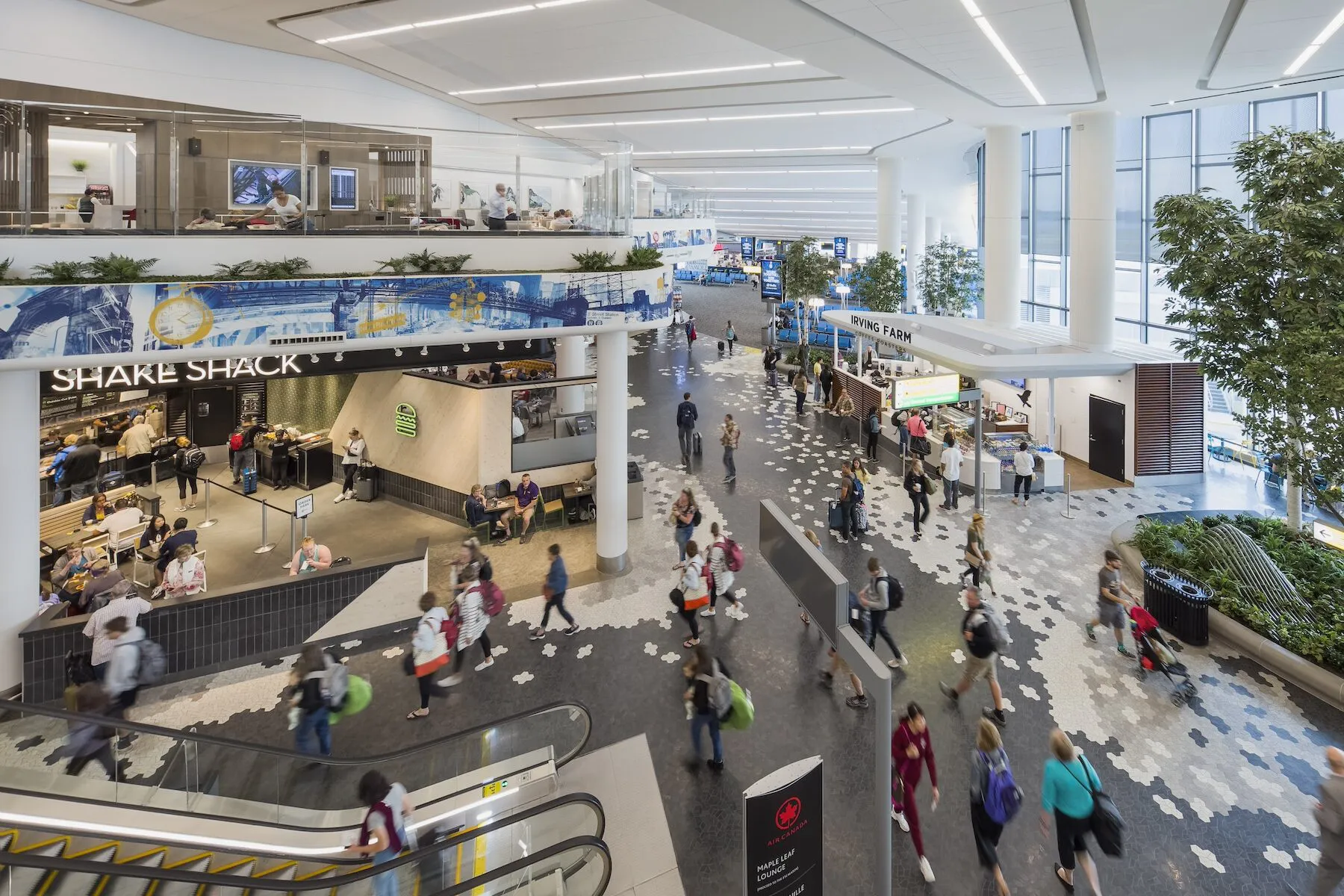 Overhead photo of LaGuardia Airport Terminal. Two floors with many people walking with motion blur.